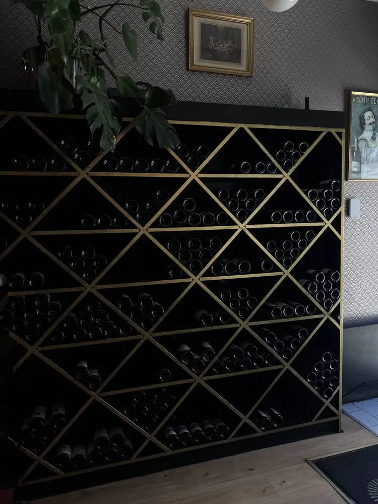 Casier à vins noir et doré rempli de bouteilles dans la salle de L'Atmosphère